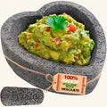 Flat base heart molcajete made of volcanic rock, filled with guacamole