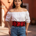 Woman wearing the red floral embroidered Mexican belt with a white off shoulder blouse