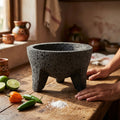 Volcanic stone molcajete on a wooden table with limes and chiles